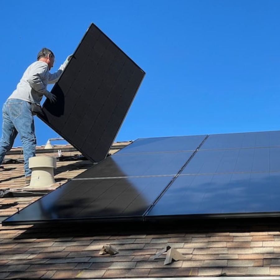 man aligning solar panels on a roof