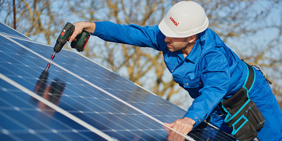 longi technician wearing white hard hat and blue utility safety clothes holding screw driver installing solar panels
